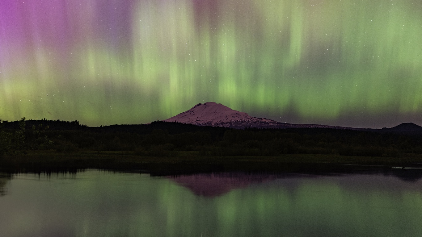 Green and magenta aurora over Mount Adams, reflected in the water
